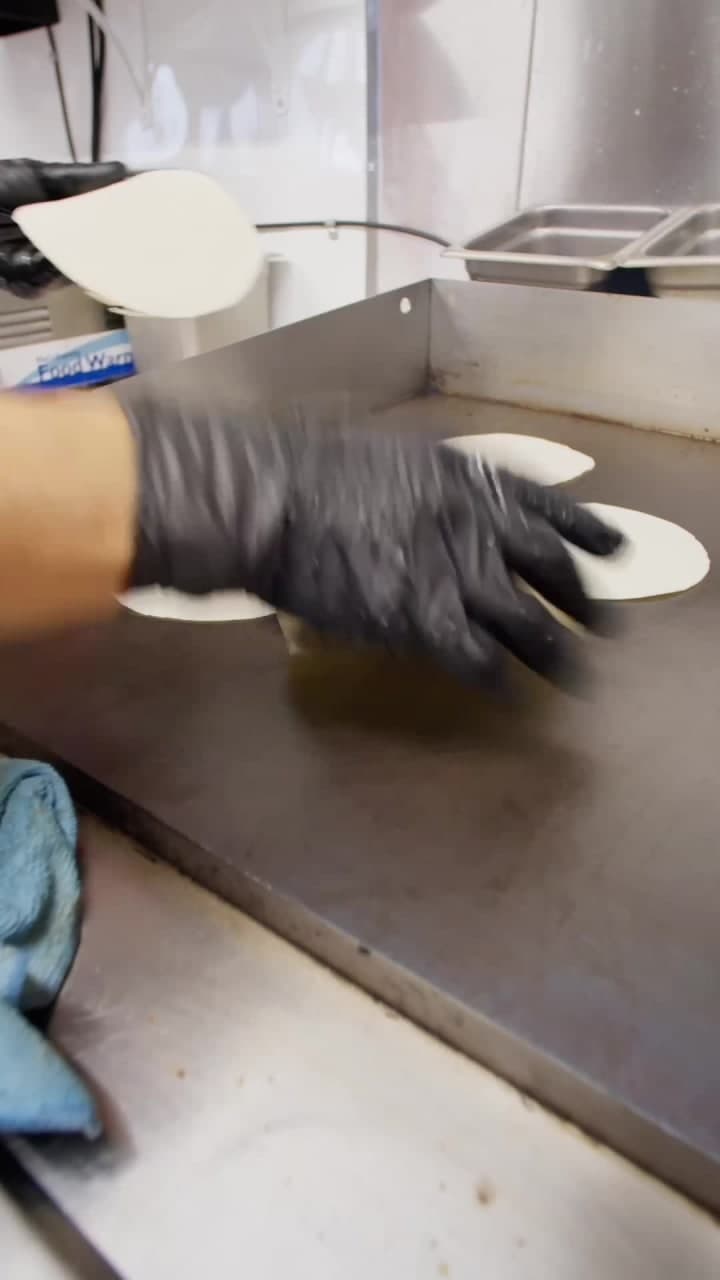 Gloved hand working the flat-top grill